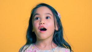 Meisje tegen oranje achtergrond dat verbazing uitdrukt