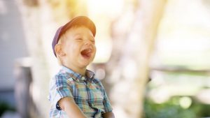 Vrolijk jochie met pet op met zijn mond wijd open