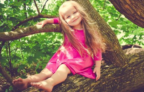 Eigenwijd kijkend meisje in een boom