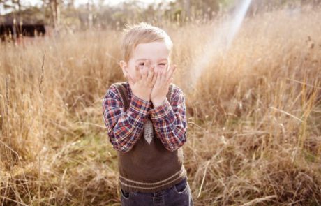 Jongetje met zijn handen voor zijn mond